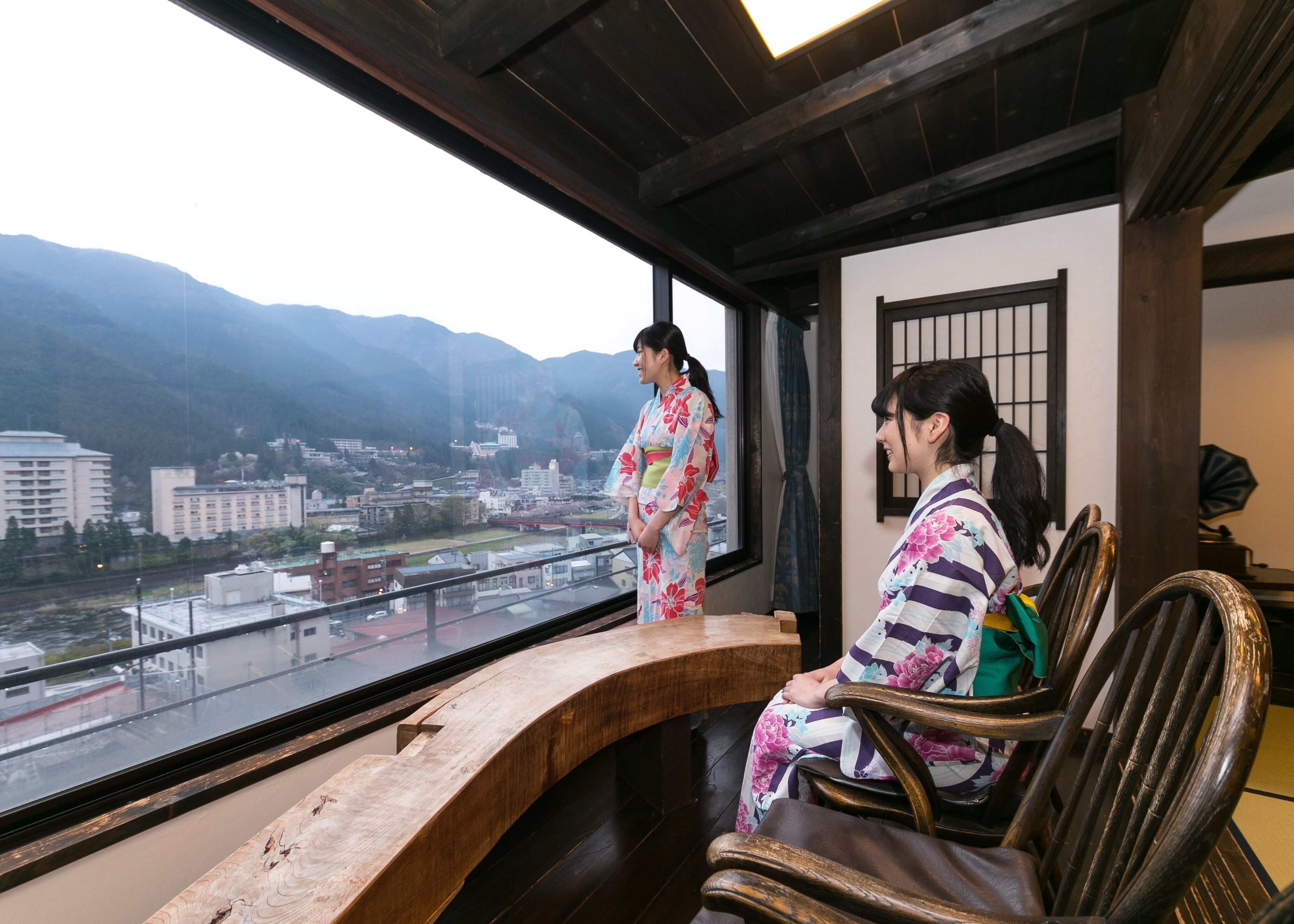 A traditional Japanese room with a view of a city and mountains.