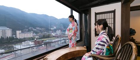 A traditional Japanese room with a view of a city and mountains.