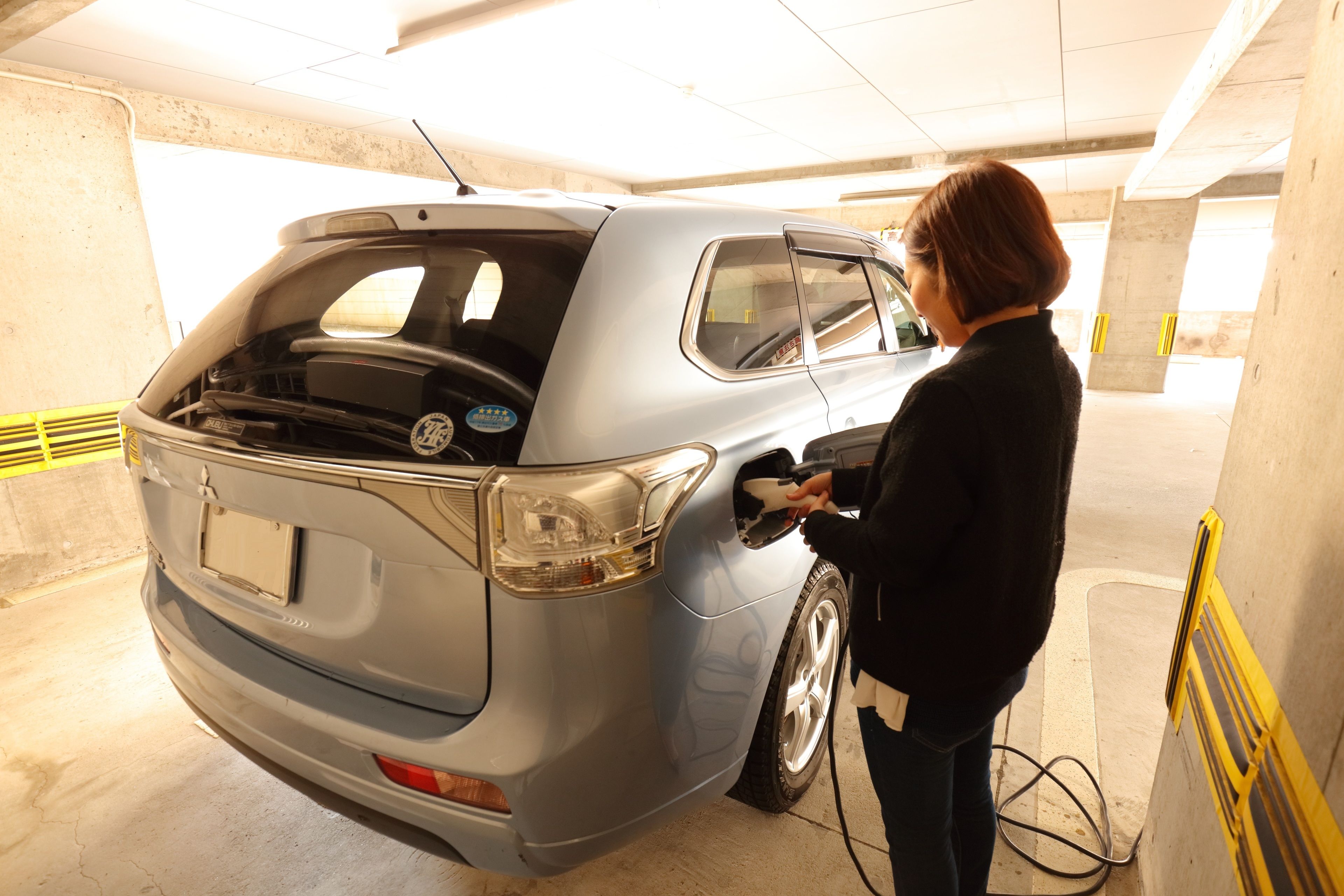 A person charging a car in a parking garage.