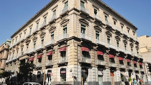 A multi-story building with a classical architectural style, featuring a symmetrical facade, multiple balconies, and storefronts at the ground level. - Catania Centro Rooms (Catania)