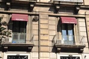 A building facade with two balconies, each with a wrought iron railing and a red awning. - Catania Centro Rooms (Catania)