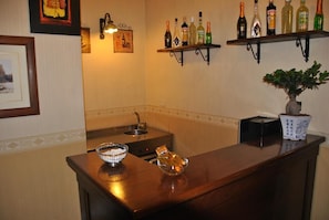 A bar area with a wooden counter, a sink, and shelves with bottles. - Catania Centro Rooms (Catania)
