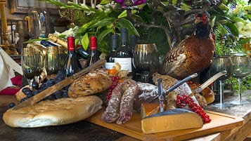 A table with various food items, including bread, cheese, and meats, along with wine bottles and glasses.