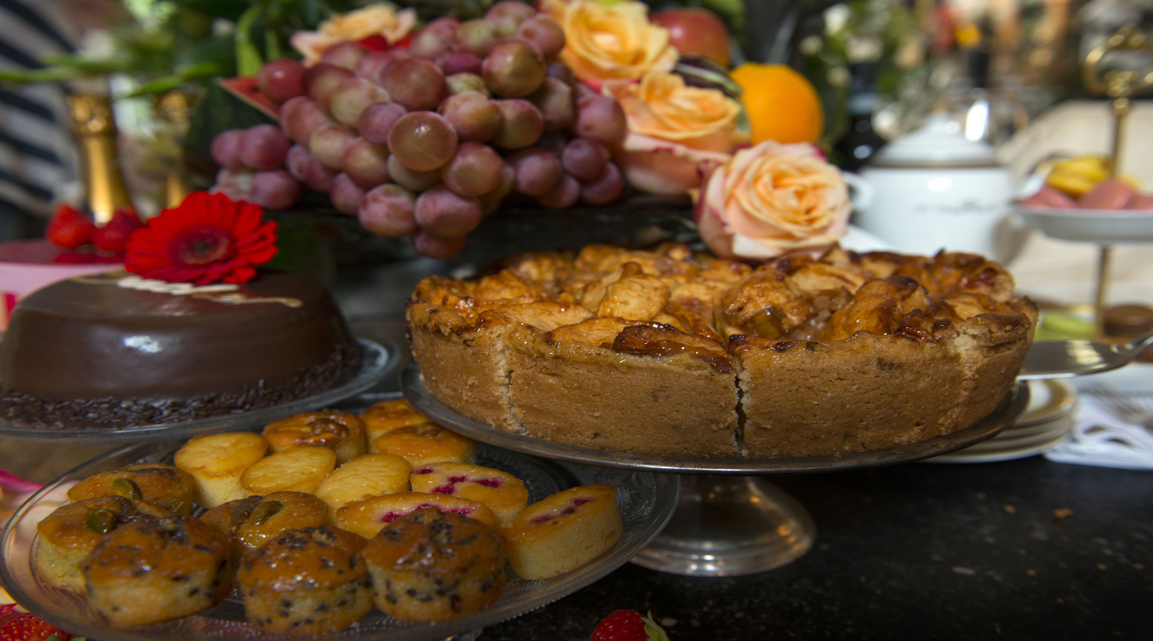 Una selezione di dolci su un tavolo, tra cui una torta al cioccolato, una torta con frutta e vari pasticcini.