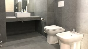 Un baño moderno con un espejo grande, un lavamanos blanco, un inodoro y un bidé.
