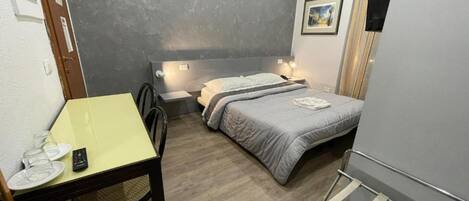 Ein kleines Schlafzimmer mit Bett, Nachttisch und einem Schreibtisch mit Stuhl.