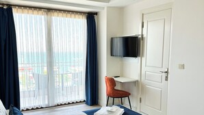 A hotel room with a bed, a desk, a TV, and a view of the city. - Büyükada Comfort Hotel (Adalar)