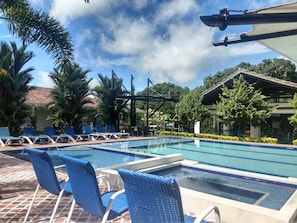 Un área de piscina con sillones de descanso y una zona de estar cubierta.
