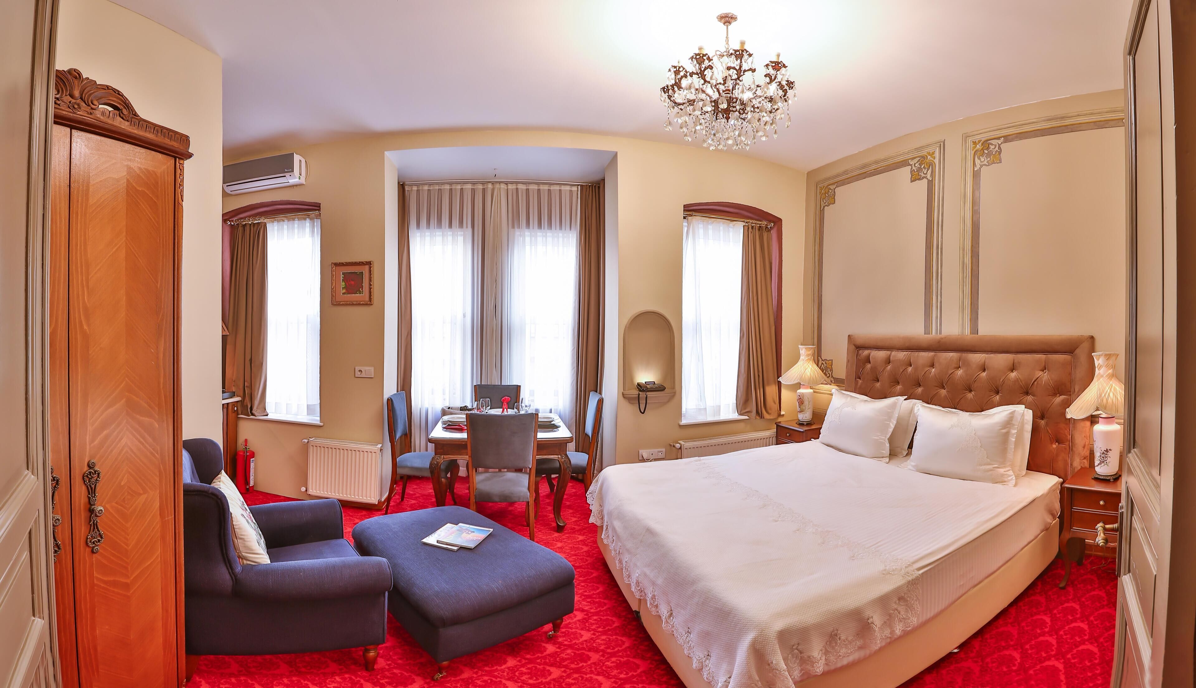 Une chambre d’hôtel avec un grand lit, une table à manger et un lustre.