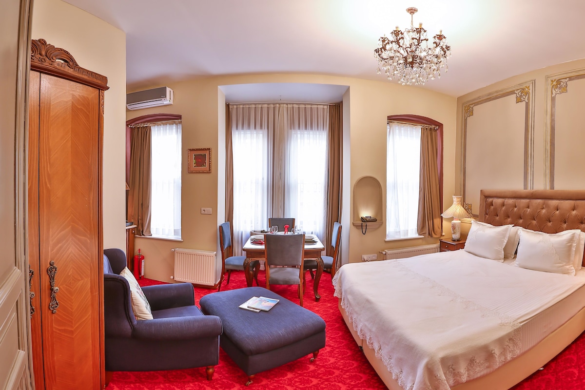 Une chambre d’hôtel avec un grand lit, une table à manger et un lustre.