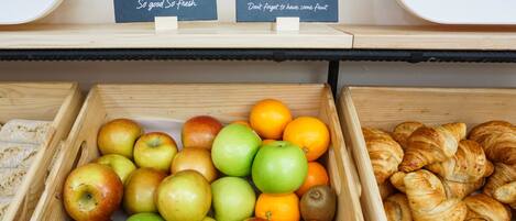 A display of fresh fruits and pastries in wooden crates with signs in Spanish.