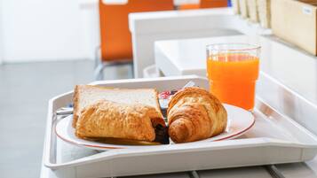 A tray with a croissant and a sandwich, and a glass of orange juice.