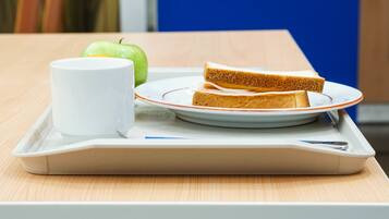 Ein Tablett mit einem Sandwich, einer Tasse und einem Apfel auf einem Tisch.