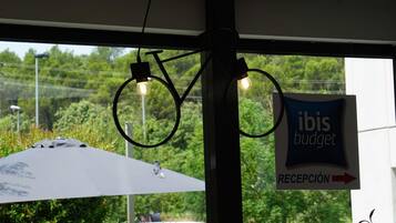 Un área de recepción con un cartel que dice 'ibis budget' y una lámpara con forma de bicicleta.