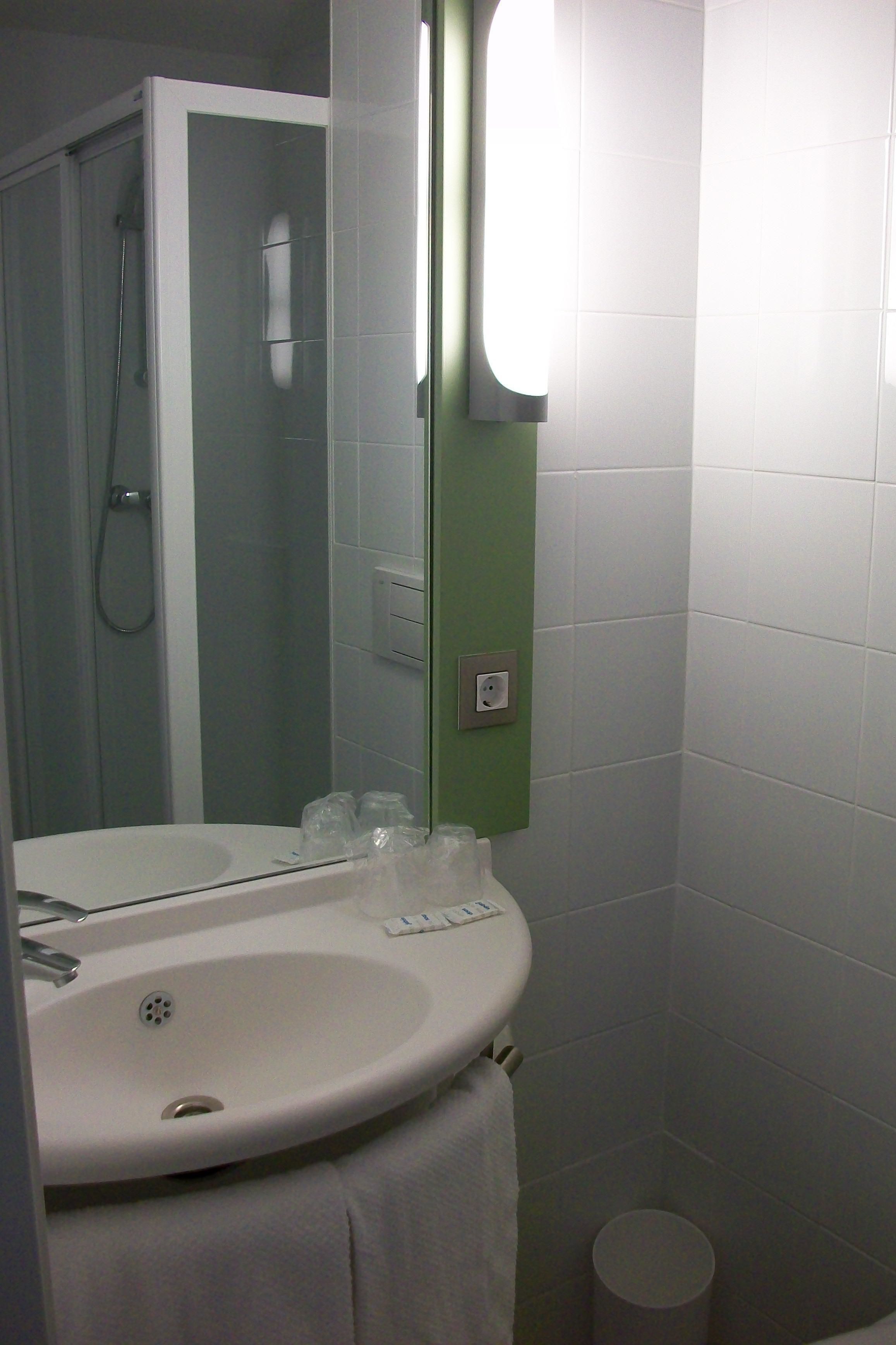 A bathroom with a white sink, a mirror, and a shower.