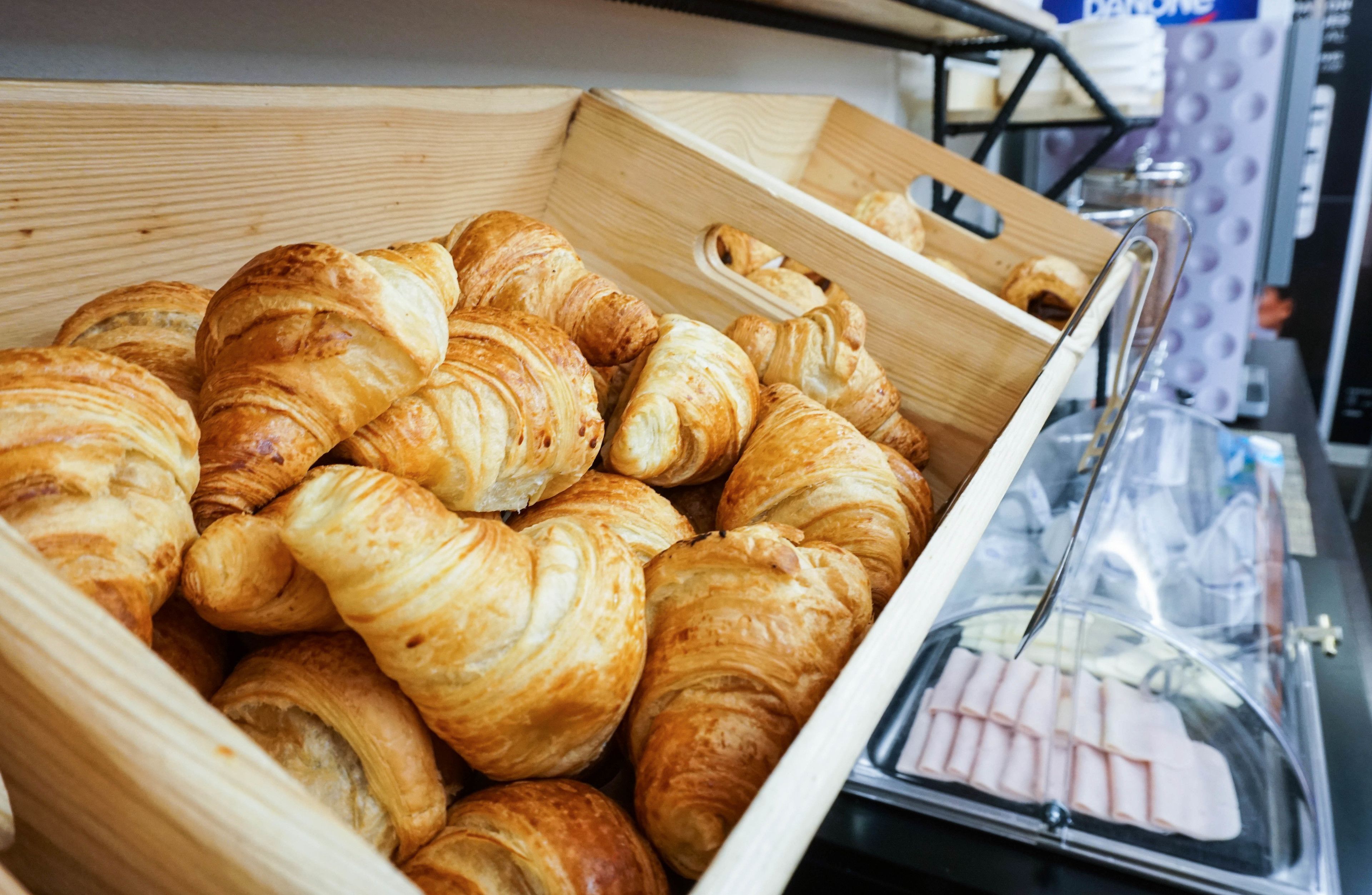 A wooden box filled with golden-brown croissants.