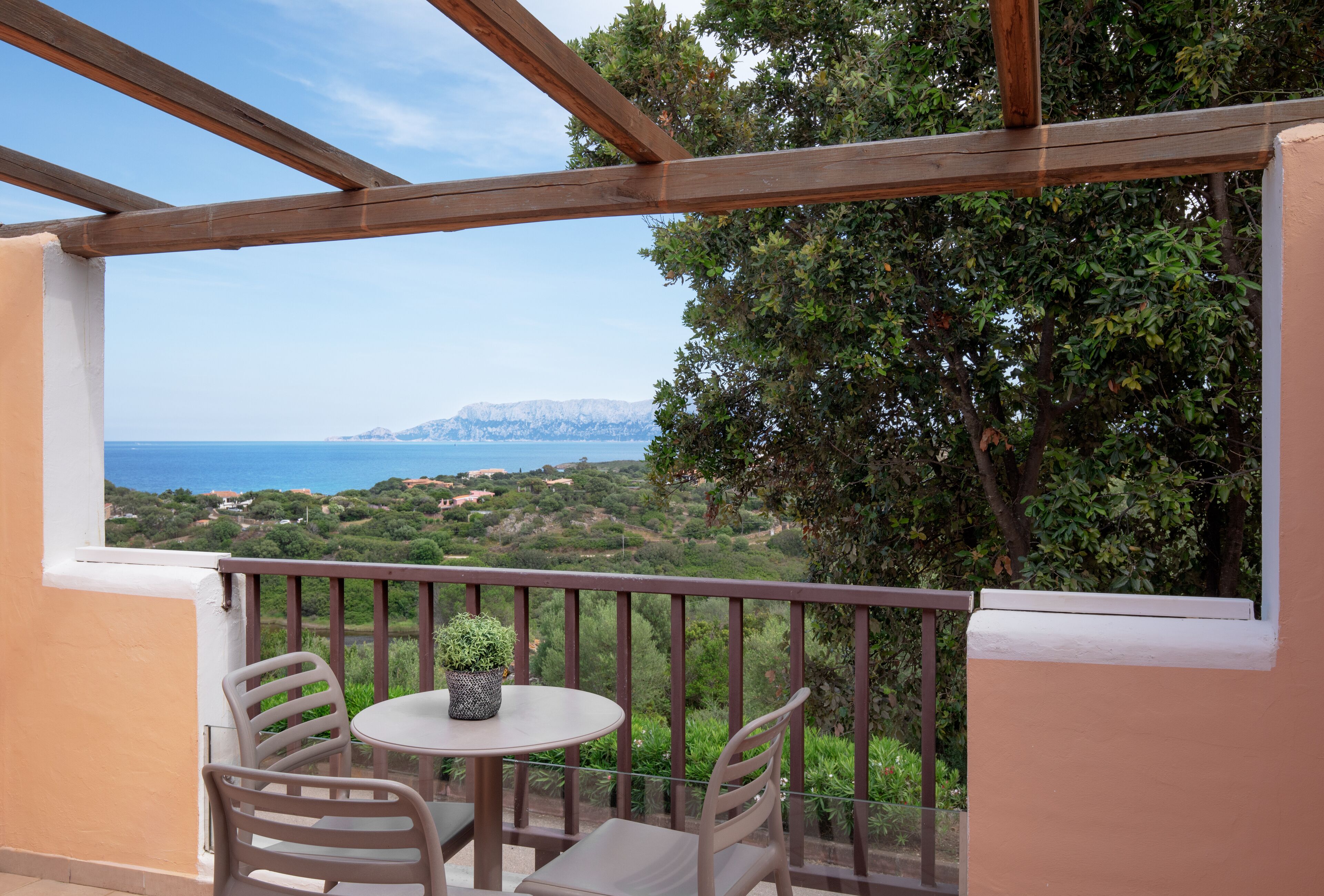 Een balkon met een tafel en stoelen, met uitzicht op een prachtig zee- en heuvellandschap.