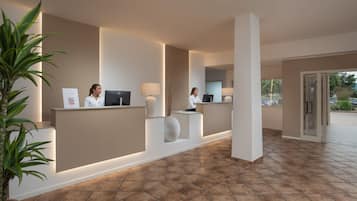 A reception area with a modern design, featuring a reception desk, a potted plant, and a large vase.