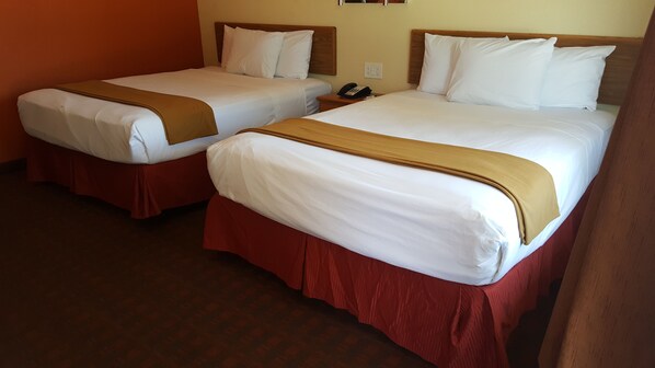 Two double beds with wooden headboards, red skirts, and white linens.