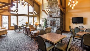 A spacious dining area with high ceilings, large windows, and a stone fireplace. - K Bar S Lodge, an Ascend Collection Hotel (Keystone)