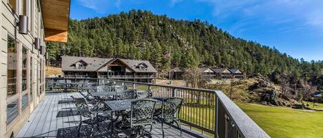 A wooden deck with outdoor seating, overlooking a forested hillside.