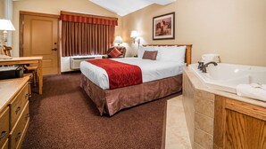 A hotel room with a bed, a desk, a chair, a window with curtains, a wall-mounted lamp, a painting, and a bathtub. - K Bar S Lodge, an Ascend Collection Hotel (Keystone)