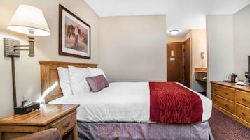 Habitación de hotel con cama, mesita de noche, lámpara y un cuadro en la pared.