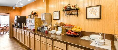 A breakfast bar with wooden cabinets, a coffee machine, and various breakfast items.