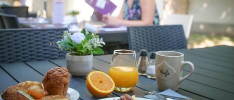 Desayuno con cruasanes, jugo de naranja y tocino sobre una mesa.