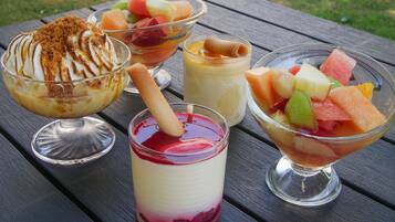 A variety of desserts on a wooden table outdoors.
