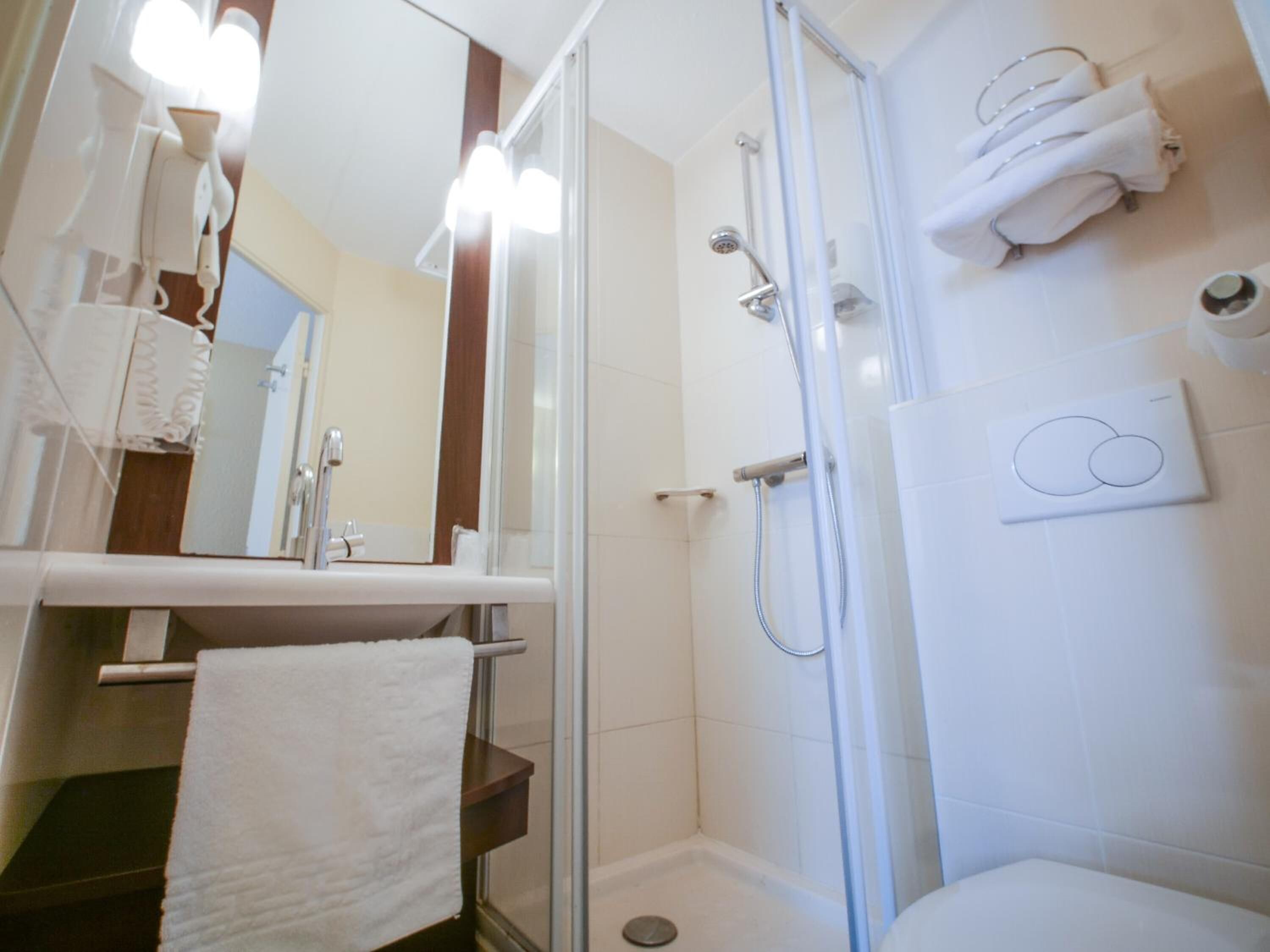 Une salle de bain moderne avec une douche à parois de verre, un lavabo blanc et un porte-serviettes.