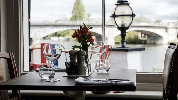 A table set for two with a view of a river and bridge. - The Swan Hotel (Staines)