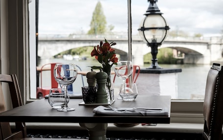 A table set for two with a view of a river and bridge.
