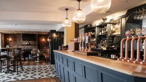 A bar area with a counter, stools, and a patterned floor. - The Swan Hotel (Staines)