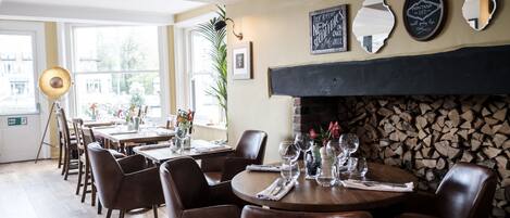A restaurant with wooden tables and chairs, a fireplace, and various wall decorations.