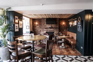 Un restaurante con mesas y sillas de madera, una pared de ladrillo y un menú en una pizarra.