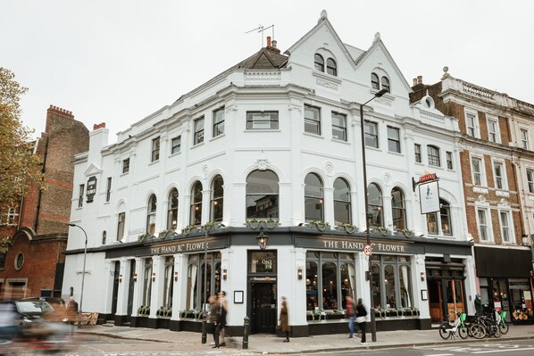 A white building with the sign "The Hand & Flower" on the ground floor.