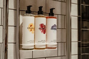Three bottles of Bramble body wash, conditioner, and shampoo on a shelf.