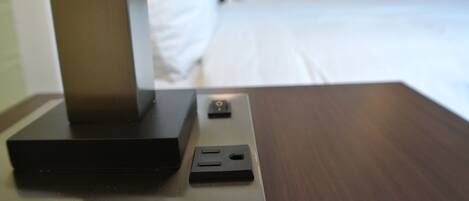 Une chambre d’hôtel avec un lit, une table de chevet avec une télévision et une prise électrique.