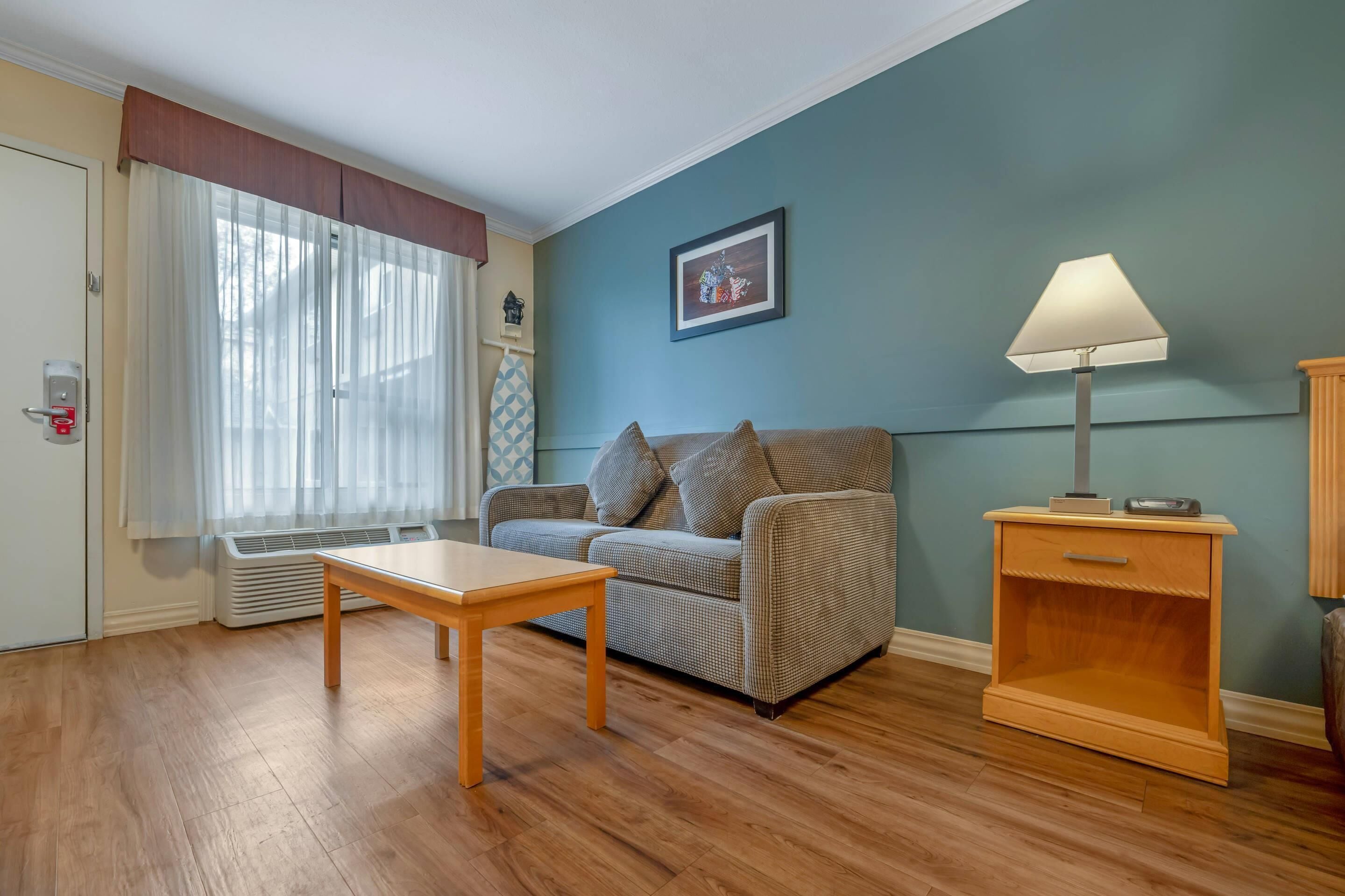 A living room with a sofa, a wooden table, a lamp, and a wall-mounted picture.