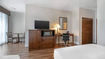 Habitación de hotel con cama, escritorio con computadora, televisión, microondas y armario.