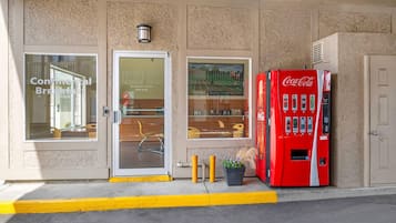 L’entrée d’un hôtel, avec un distributeur automatique de Coca-Cola, une porte vitrée et une fenêtre donnant sur l’intérieur.