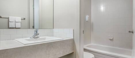 A bathroom with a sink, mirror, toilet, and bathtub.