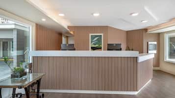 A reception desk with a modern design, a glass table with a plant, and a view of the outside.