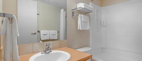 A bathroom with a sink, mirror, towel rack, and a shower area.