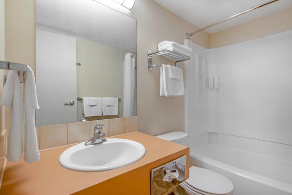 Baño con lavabo, espejo, toallero y zona de ducha.