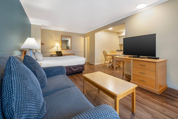 A hotel room with a bed, a sofa, a television, a desk, and a chair. - Econo Lodge Inn & Suites Kelowna (Kelowna)