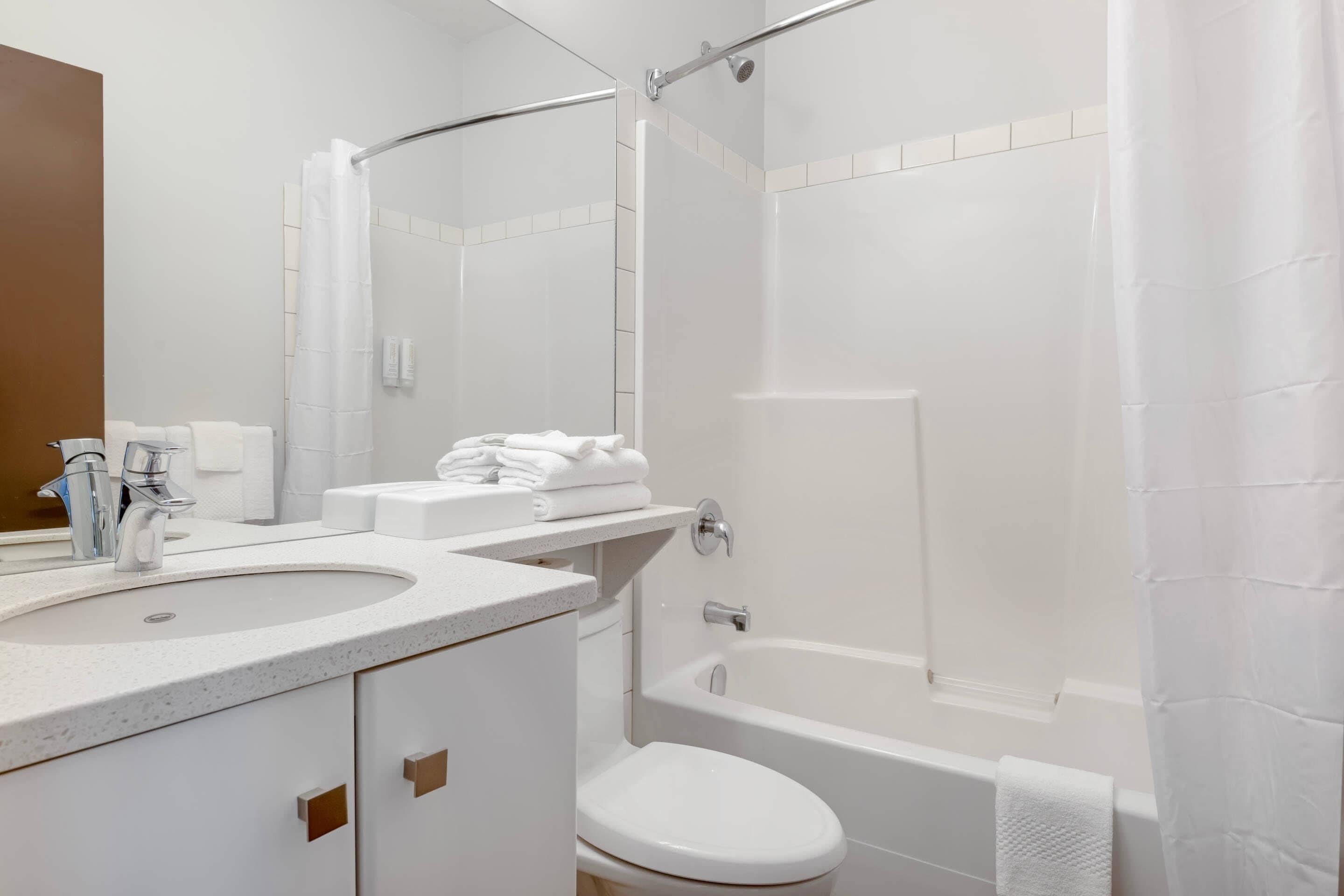 Un baño con lavamanos, inodoro, bañera y cortina de ducha.