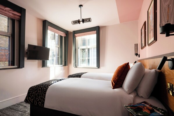A hotel room with a large bed, two windows with shutters, a flat-screen TV mounted on the wall, and a ceiling light fixture. - The Wellington Hotel (London)