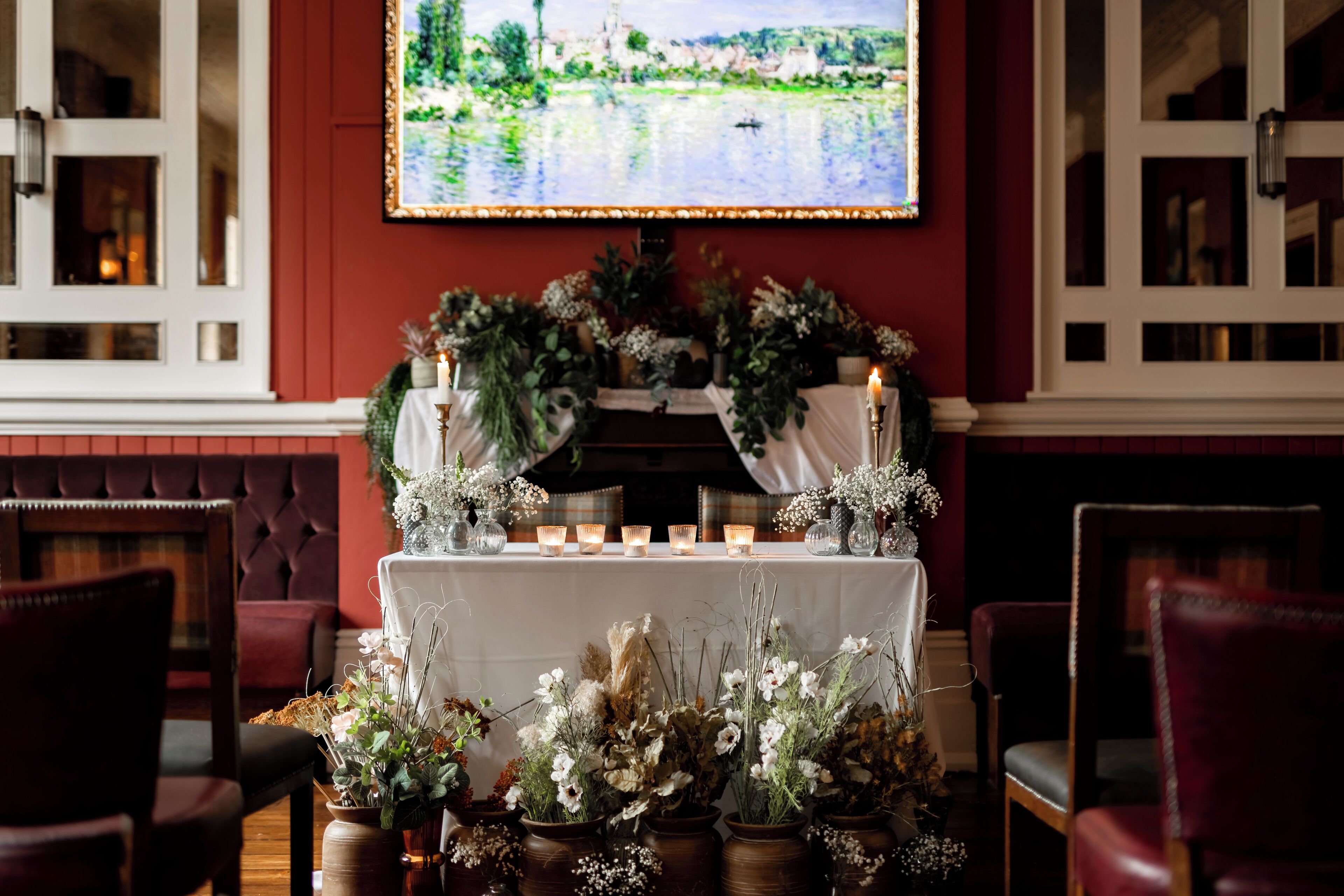A room with a table set for a meal, surrounded by chairs, and a television mounted on the wall displaying a scenic view.